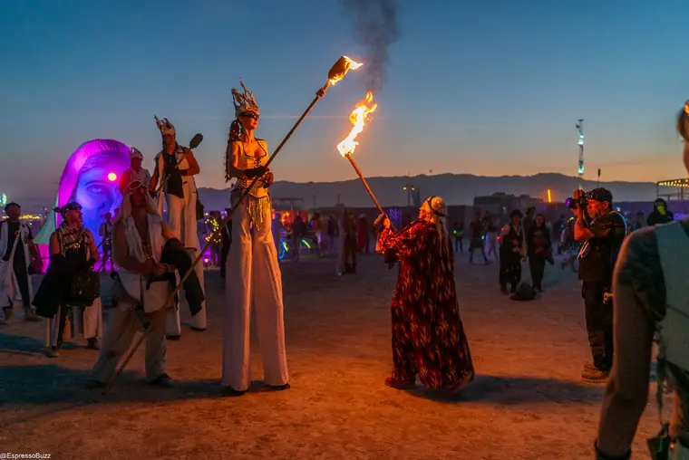 Fire stilt walking in a crimson costume at Burning Man